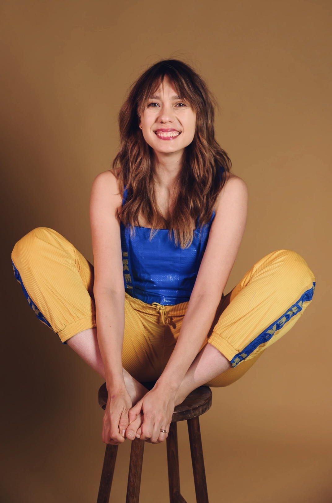 Lilla Multipass sitting on a stool in yellow trousers and a blue IKEA bag top